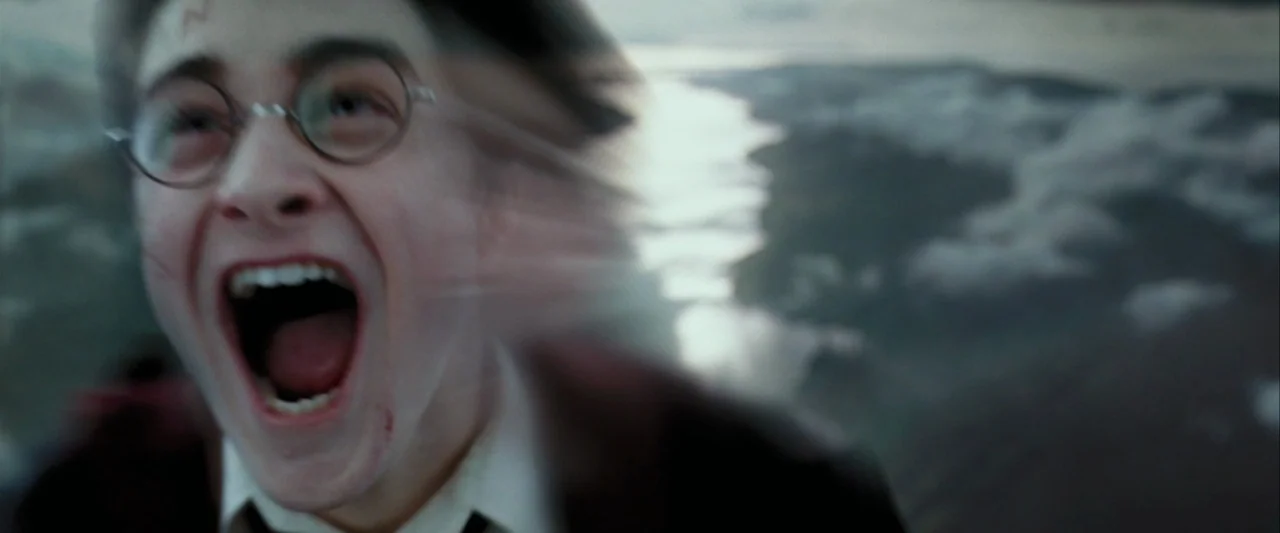 Harry Potter and the Prisoner of Azkaban (2004) movie still: closeup — A teenage boy is falling through the sky above a cloudy landscape. He has his…