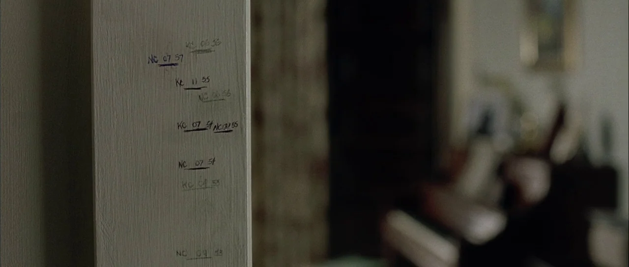 Capote (2005) movie still: closeup — A close-up of a white painted door frame with handwritten ink markings. Multiple names and numbers are written…