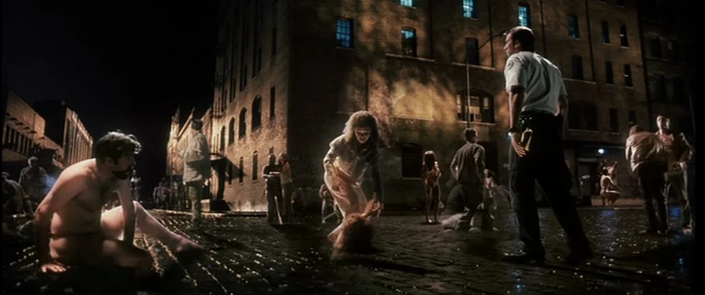 Bringing Out The Dead (1999) movie still: wide — A nighttime city street paved with cobblestones is illuminated by warm, artificial light sources. A…