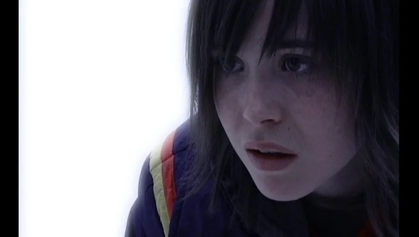 The Tracey Fragments (2007) movie still: closeup — A person is centered against an undifferentiated, pure white void. The subject looks off-camera…