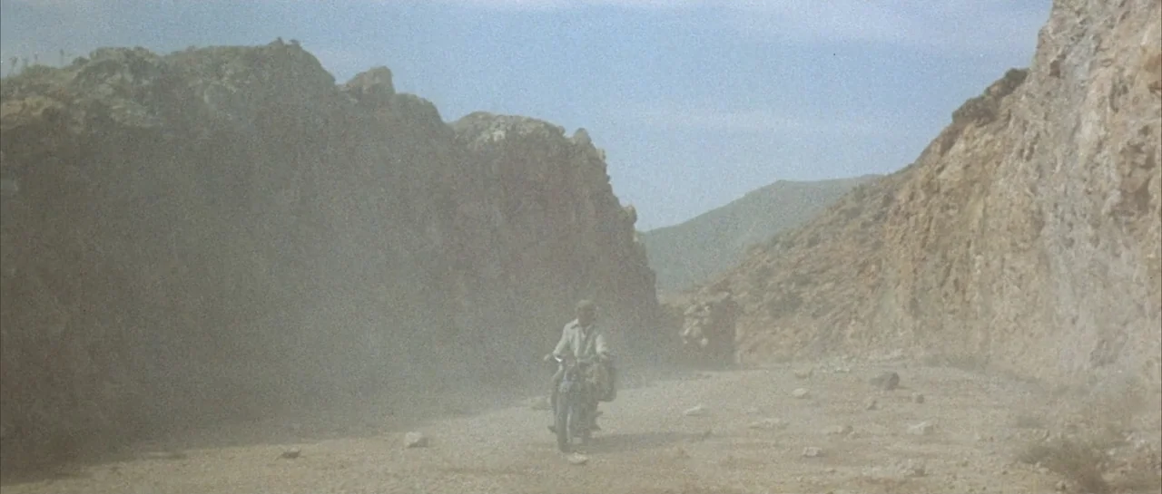 Duck, You Sucker (1971) movie still: wide — A dry, rocky canyon passage features steep, uneven walls and a dusty gravel floor. A lone motorcyclist…