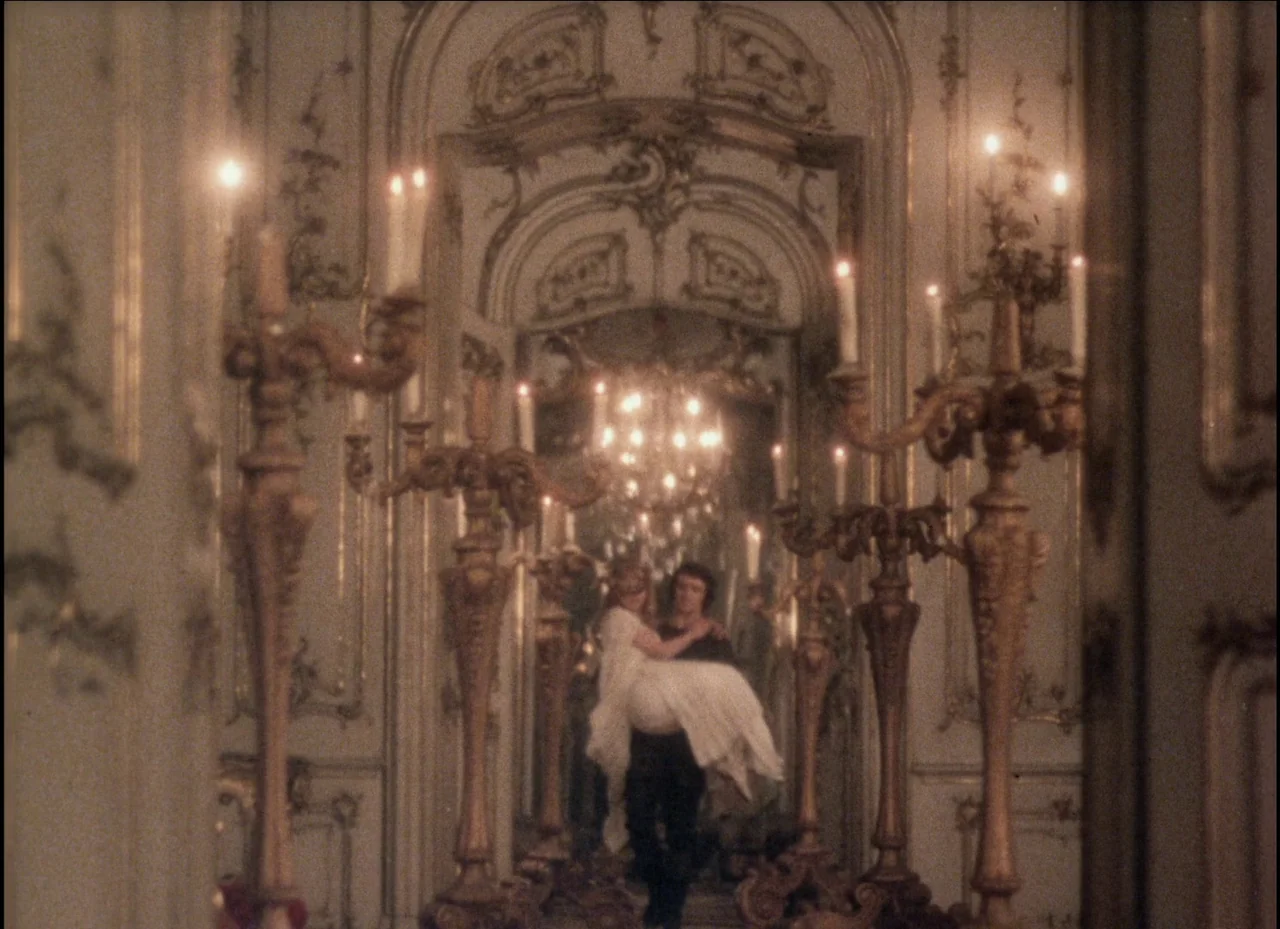 Beauty and the Beast (1979) movie still: wide — An opulent, highly detailed hallway features gilded moldings and multiple large mirrors. A man…