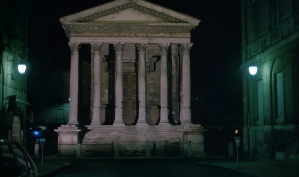 Vagabond (1985) movie still: establishing — A Roman-style temple with Corinthian columns sits at the end of a dark street. The building is…