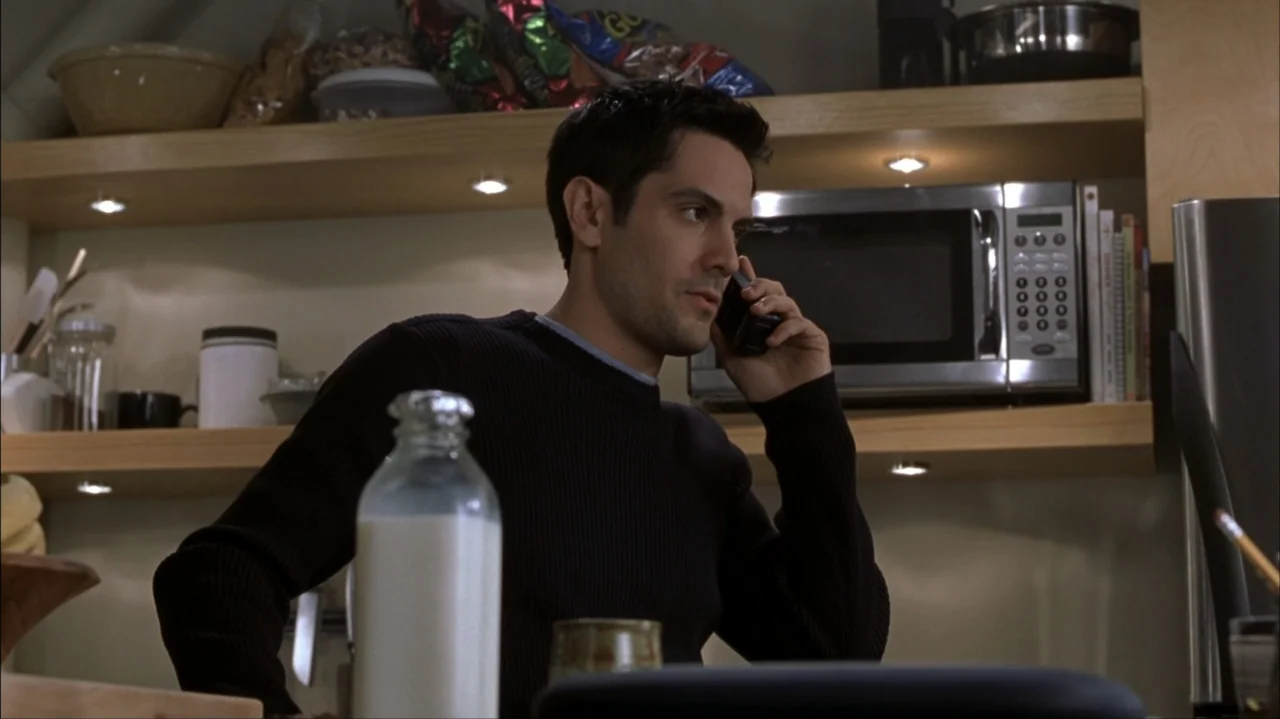 Final Destination 2 (2003) movie still: medium — A modern home setup with wood shelving and a stainless steel microwave behind. A man with dark hair…
