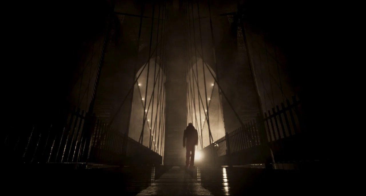 Motherless Brooklyn (2019) movie still: wide — A dark night on a suspended bridge with tall gothic arch supports visible ahead. A lone figure walks…