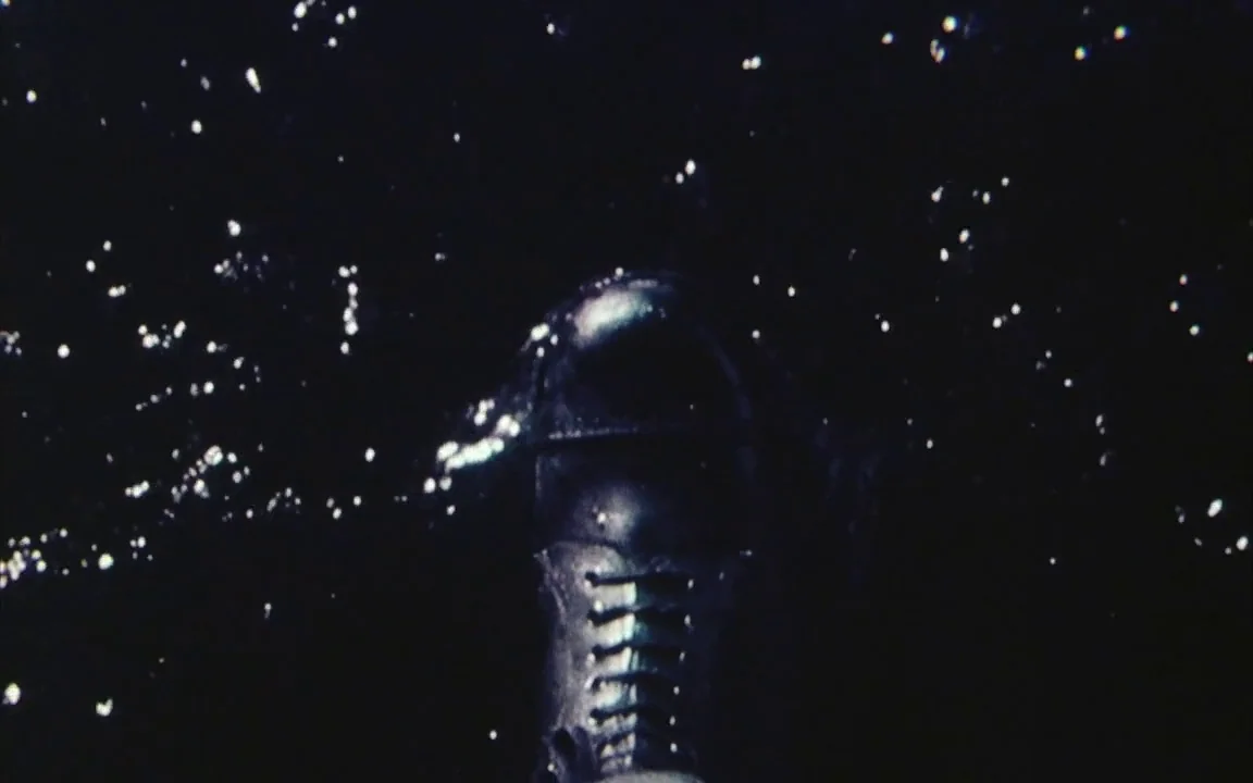 The Last of England (1987) movie still: closeup — A dark, deep expanse of water is punctuated by droplets thrown into the air. A single dark leather…