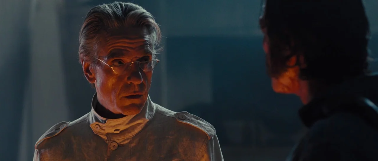 High-Rise (2015) movie still: medium — A dimly lit, sparse environment with industrial textures suggesting a sterile technical facility. An older…