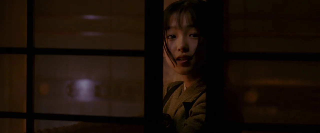 Memoirs of a Geisha (2005) movie still: closeup — A dark indoor space viewed through the vertical and horizontal bars of a door. A young girl stands…
