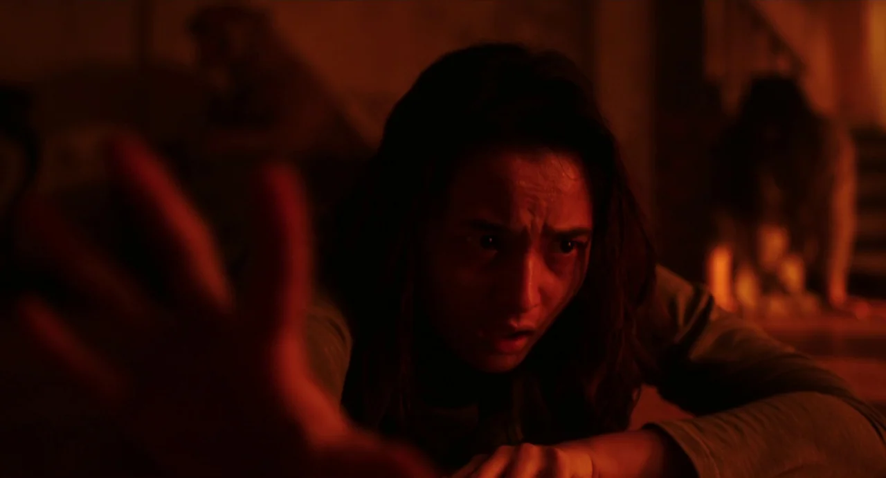 May The Devil Take You (2018) movie still: closeup — A dimly lit, red-saturated environment with indistinct shapes in the background. A young woman…