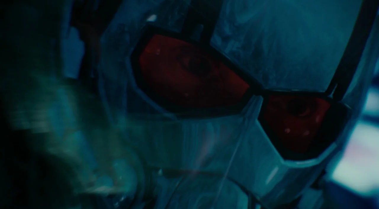 Ant-Man (2015) movie still: closeup — A dark, technological setting with blue light reflecting off a polished helmet surface. A person's eyes appear…