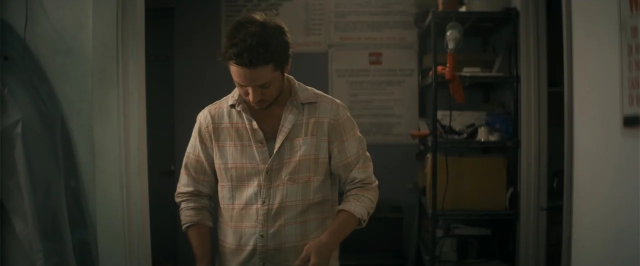 Holiday Harmony (2022) movie still: medium — A cluttered storage room contains metal shelving units filled with various items and paperwork. A man…