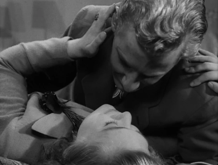 Port of Call (1948) movie still: closeup — A dimly lit indoor space where two figures lean close to one another. The man rests a hand on the woman's…