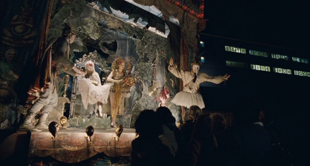 The Imaginarium of Doctor Parnassus (2009) movie still: wide — A nighttime outdoor fairground features a small, heavily decorated proscenium stage…