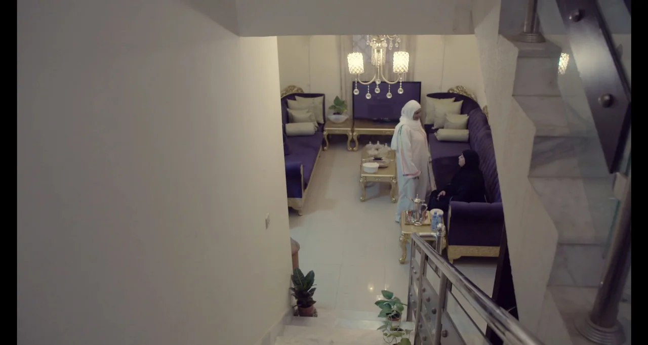 Saudi Women's Driving School (2019) movie still: wide — A furnished interior featuring purple velvet couches and a gold-accented television console.…