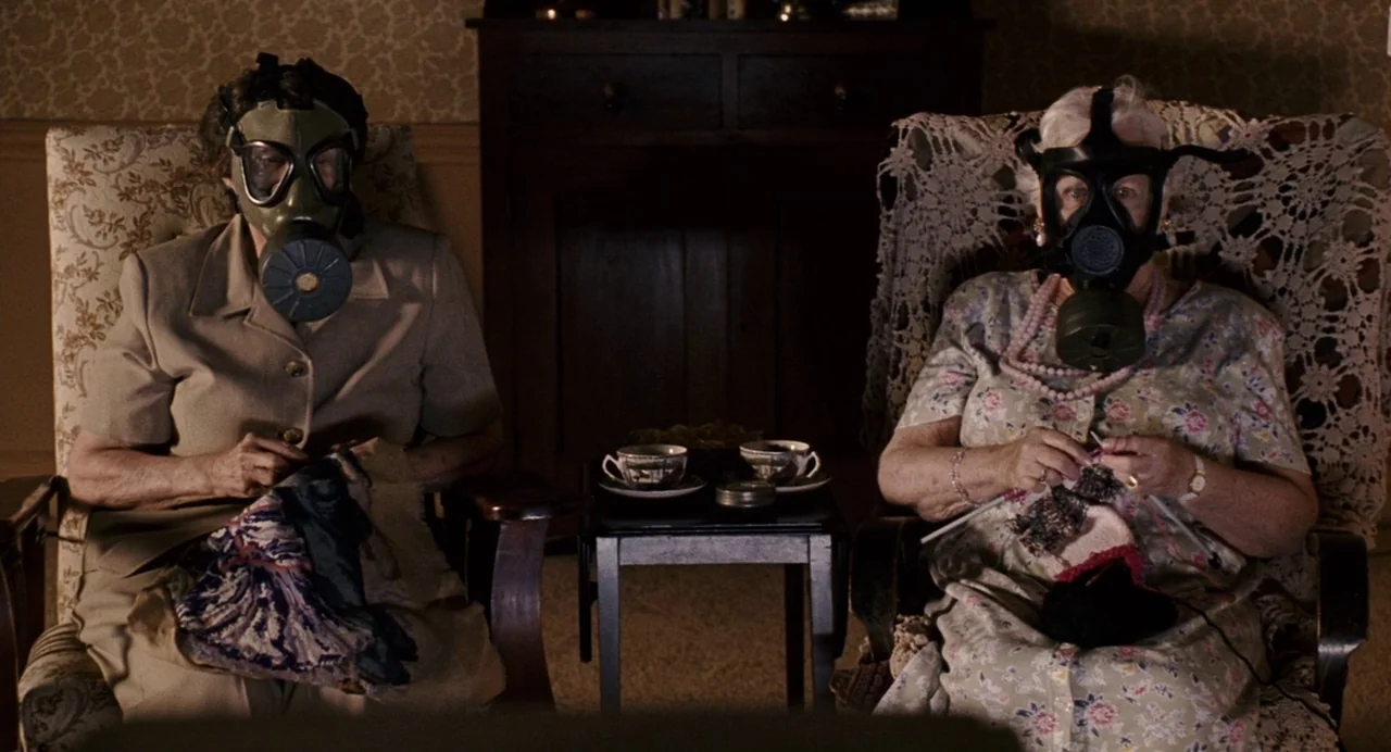 The Happening (2008) movie still: medium — A domestic space features wallpaper and two armchairs with lace doilies on the backs. Two women in gas…