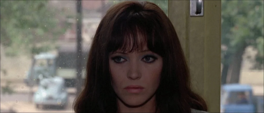 Made in U.S.A. (1966) movie still: closeup — The interior of a vehicle during the day with a window framing the view. A woman with dark hair and…
