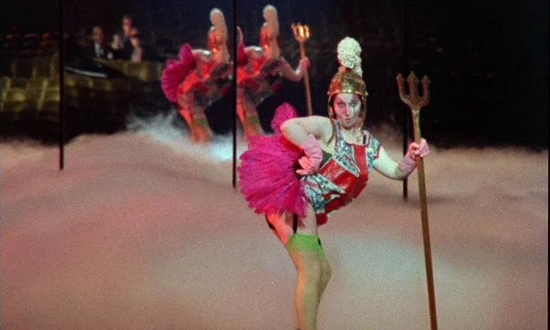 Jubilee (1978) movie still: fullbody — A theatrical stage covered in low-lying fog with performers in costume. The central performer balances on one…