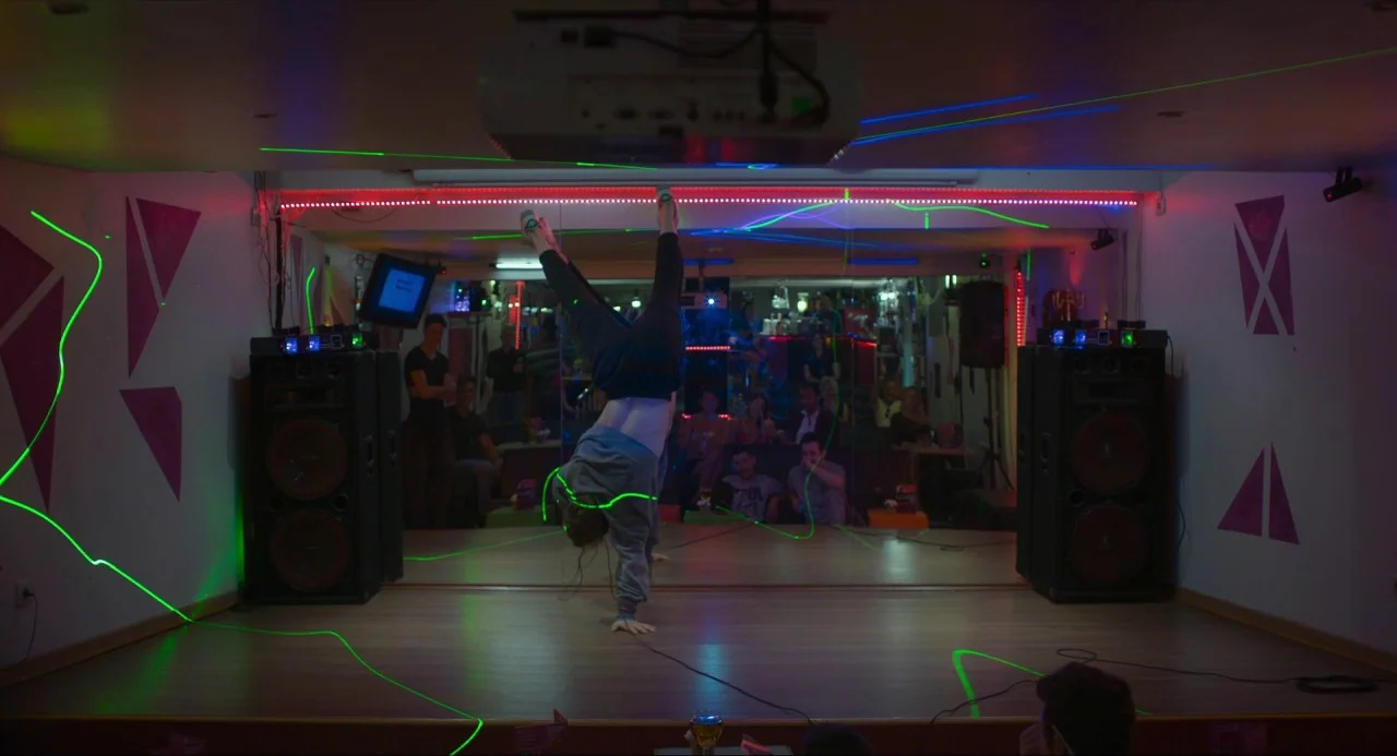 Happy End (2017) movie still: fullbody — A dance studio interior features wooden flooring and mirrors reflecting a seated audience. A male dancer…
