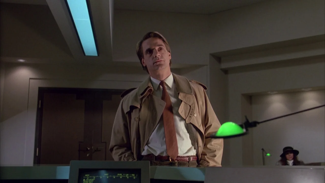 Dead Ringers (1988) movie still: medium — A dark, modern control room features panels with monitors and geometric architectural lines. A man in a…