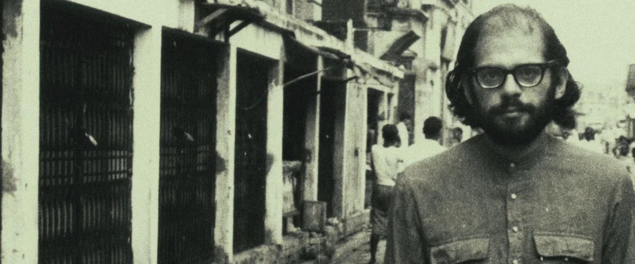 Kill Your Darlings (2013) movie still: medium — A narrow stone alley features shuttered storefronts and peeling plaster walls. A man in eyeglasses…