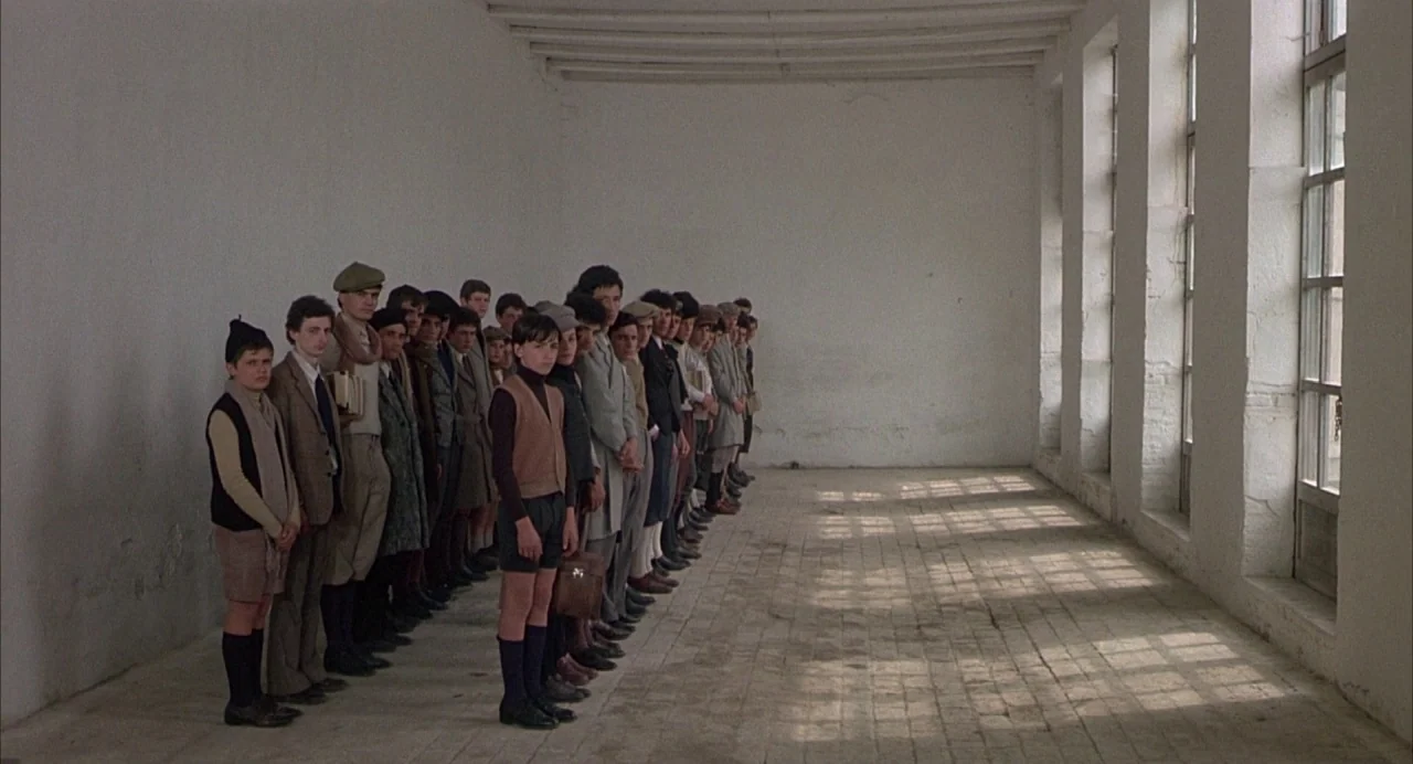 Salò, or the 120 Days of Sodom (1975) movie still: wide — A long minimalist corridor with white plaster walls and a light-colored brick floor. A…