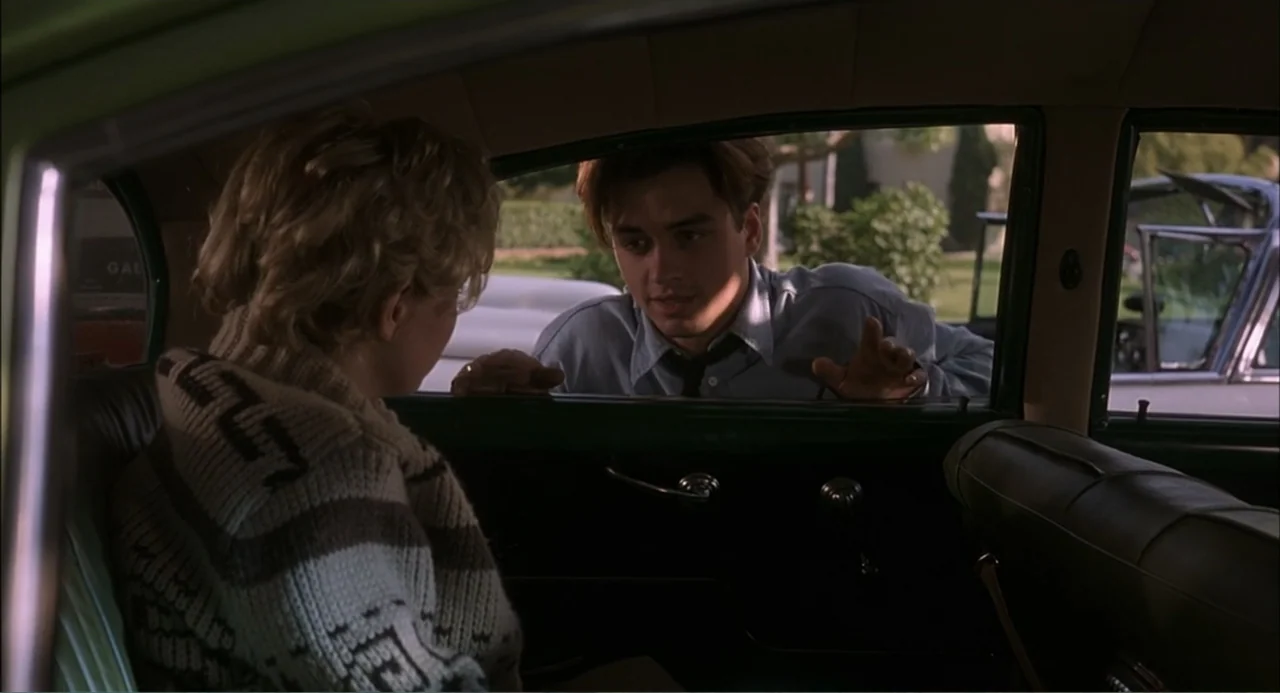 Wild Orchid II: Two Shades of Blue (1991) movie still: medium — The interior of a vehicle serves as the setting for a conversation. A young man…