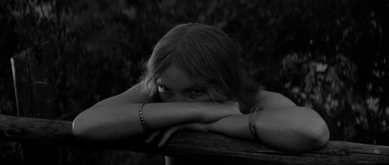 Andrei Rublev (1966) movie still: closeup — A person leans forward against a weathered wooden rail in an outdoor area. The subject rests their chin…