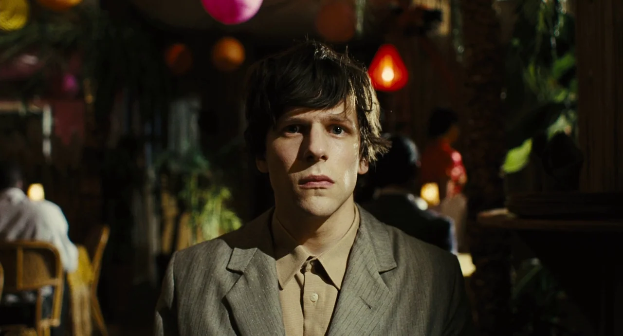 The Double (2013) movie still: medium — A dimly lit dining space is decorated with colorful paper lanterns. A young man sits at a table and stares…