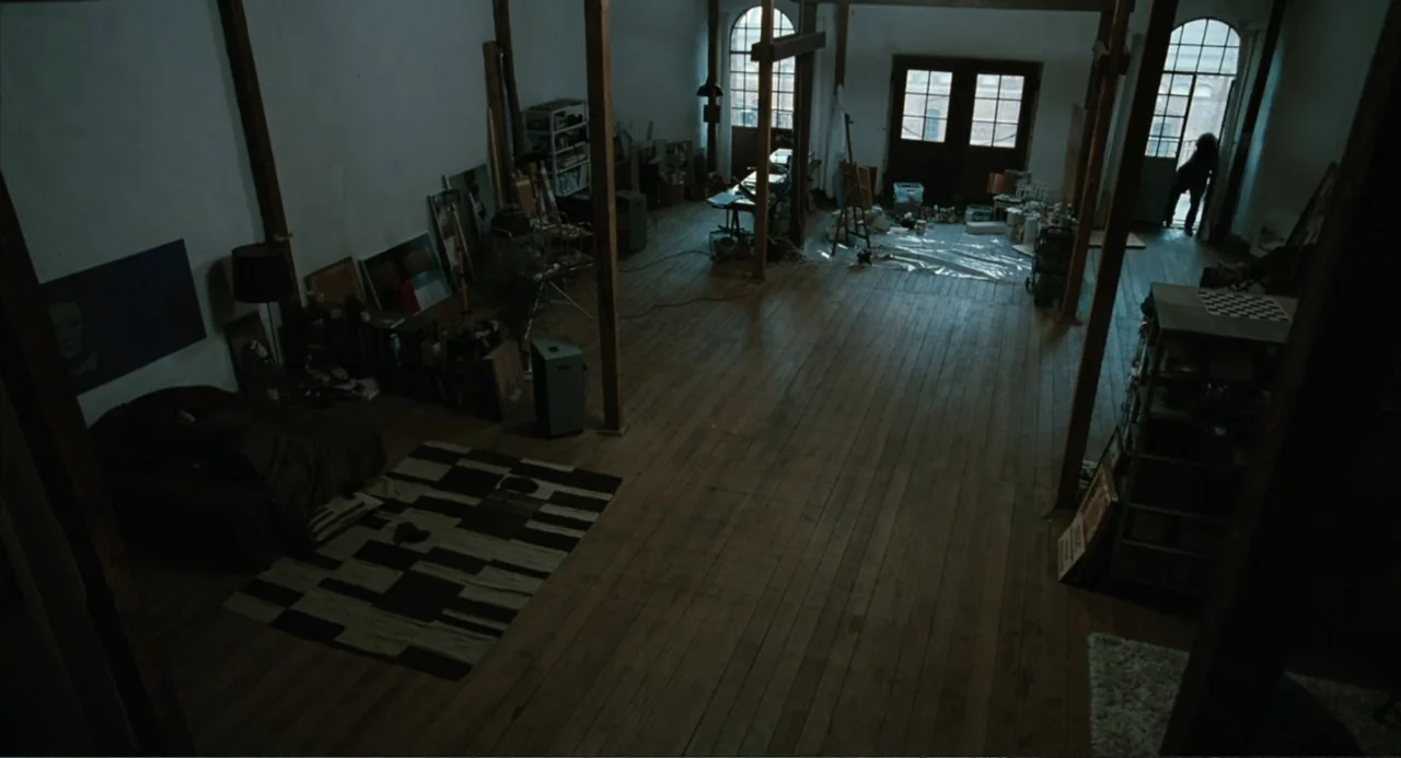 Soul Kitchen (2009) movie still: wide — A large, open-plan artist studio with exposed wooden support beams and hardwood floors. A distant figure…