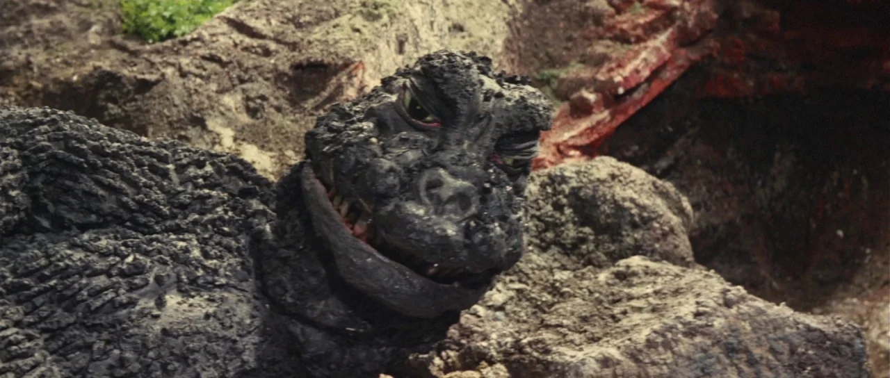 Son of Godzilla (1967) movie still: closeup — A rocky, barren outdoor terrain with uneven ground and loose stone formations. A large, reptilian…