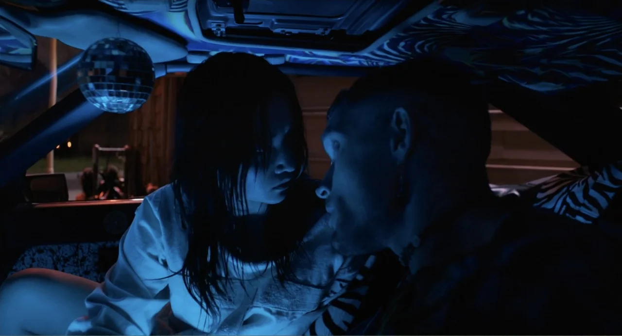 Mona Lisa and the Blood Moon (2022) movie still: medium — A dark vehicle interior features a small disco ball hanging from the roof frame. A man and…