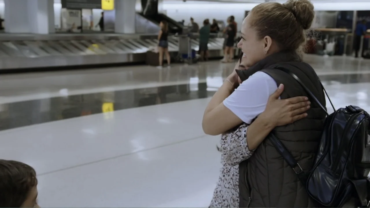 Torn Apart: Separated at the Border (2019) movie still: medium — An airport terminal with a luggage carousel and distant travelers in the…