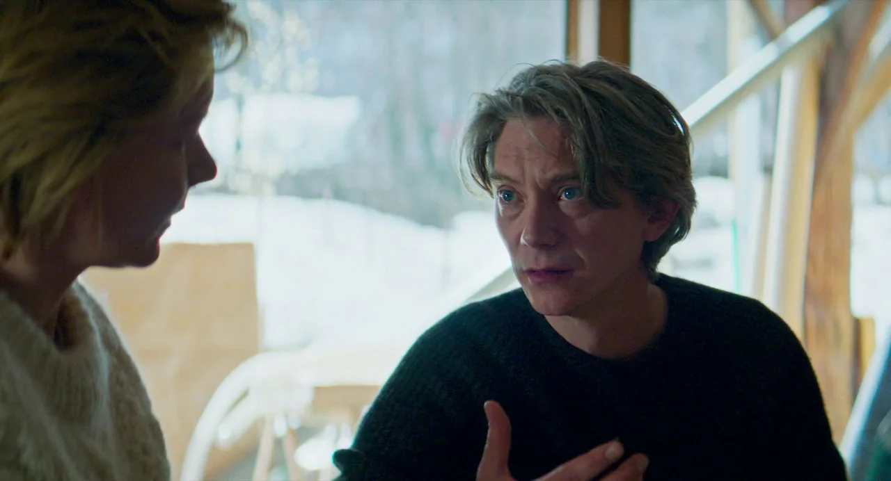 Anatomy of a Fall (2023) movie still: medium — An interior space with a large window looking out onto a snow-covered landscape. A man and a woman…