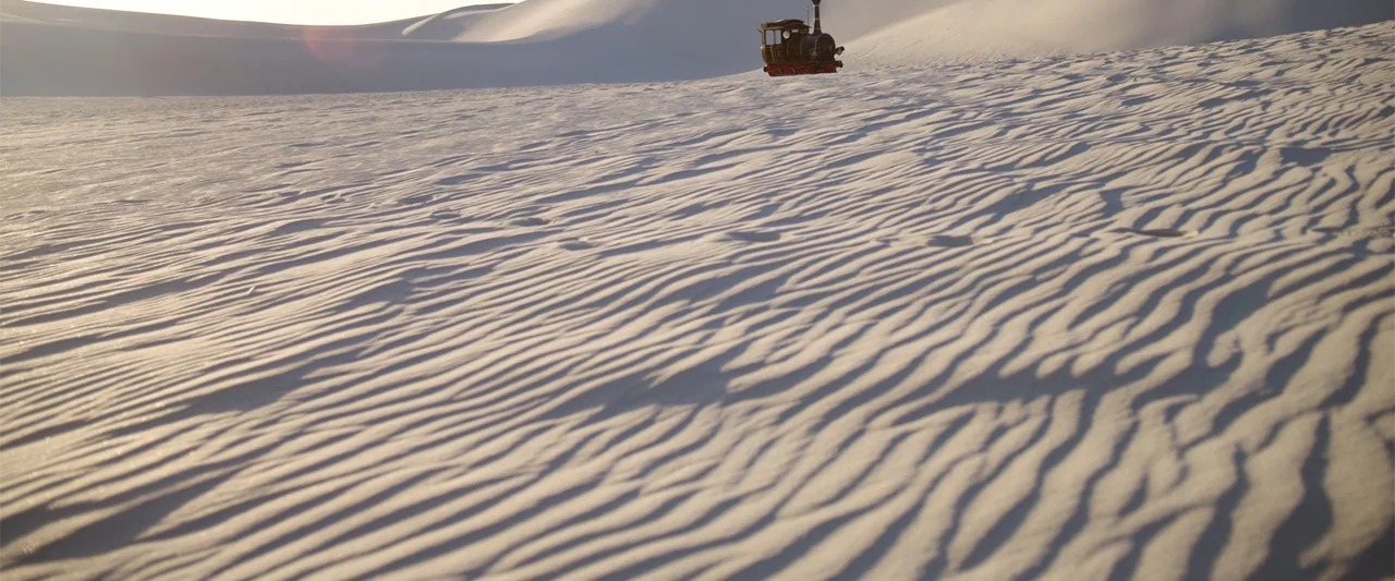 Jim Button and Luke the Engine Driver (2018) movie still: establishing — Vast undulating sand dunes stretch toward the horizon under a low sun. A…