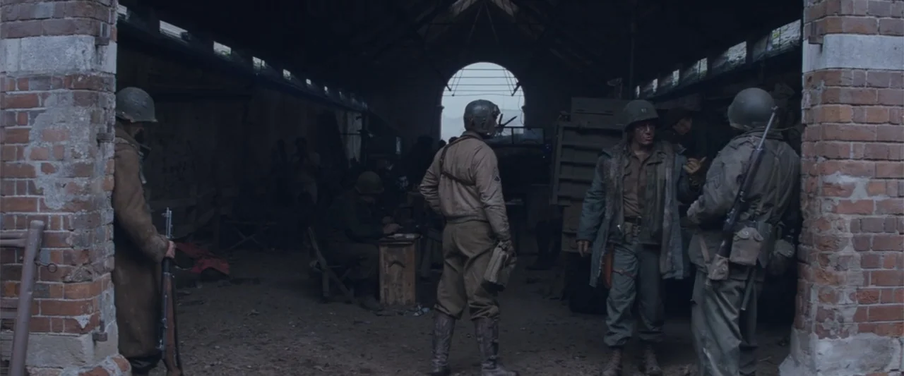Fury (2014) movie still: wide — A dark, cavernous brick structure houses several military personnel in 1940s gear. Soldiers in helmets and uniforms…
