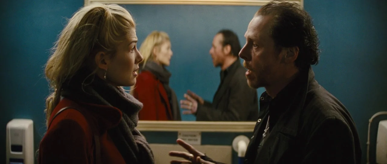 The World’s End (2013) movie still: medium — A dimly lit restroom with dark teal walls features a large central mirror. Two people stand before the…