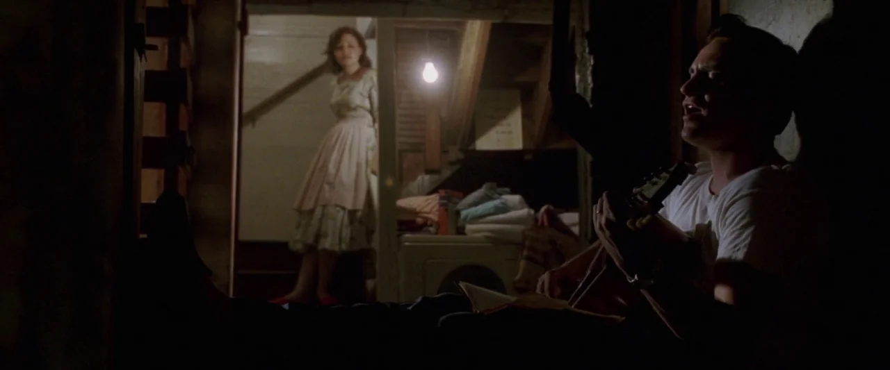 Walk The Line (2005) movie still: medium — A dark, cluttered basement contains a laundry area and a wooden staircase. A man sits in the foreground…