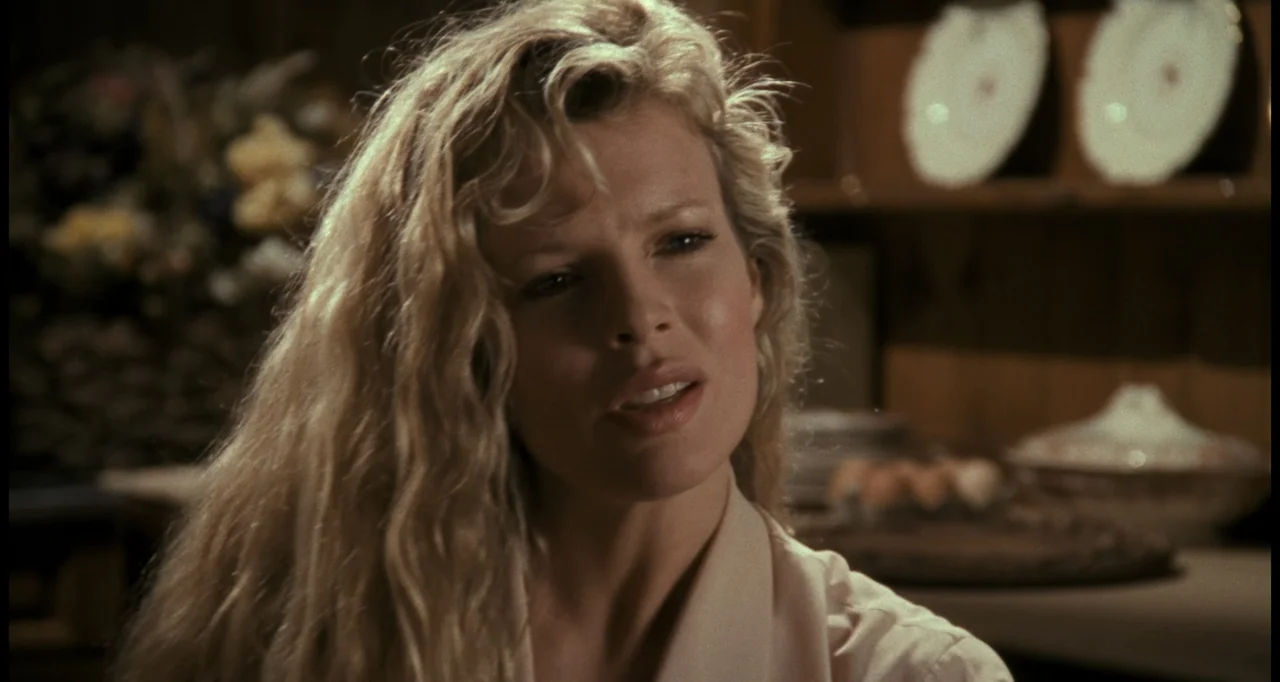 Batman (1989) movie still: closeup — An interior kitchen setting featuring a person centered in a softly lit room. A woman with wavy blonde hair…