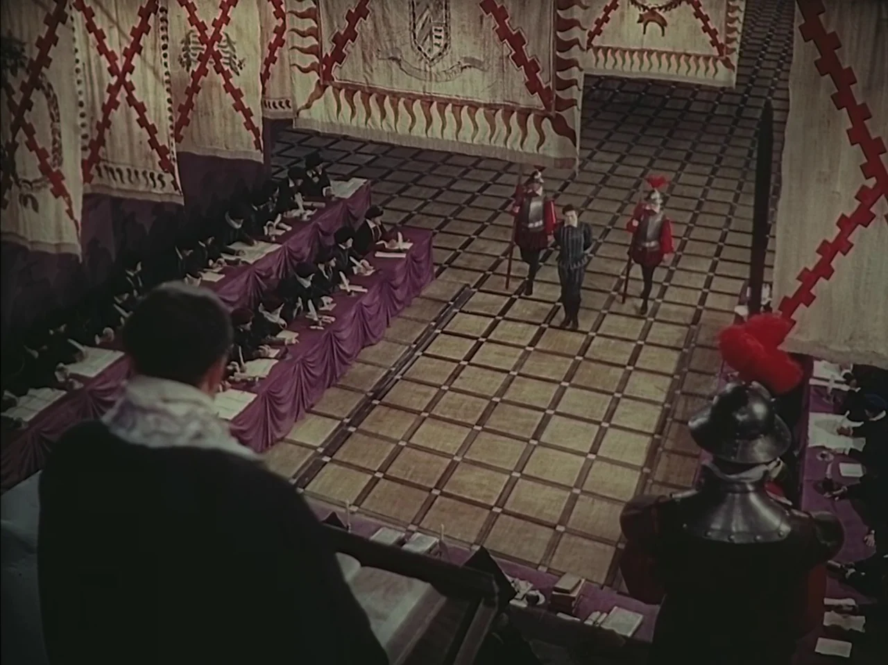 Pandora and the Flying Dutchman (1951) movie still: wide — A vast hall features a checkered floor and rows of seated officials behind tables. A man…