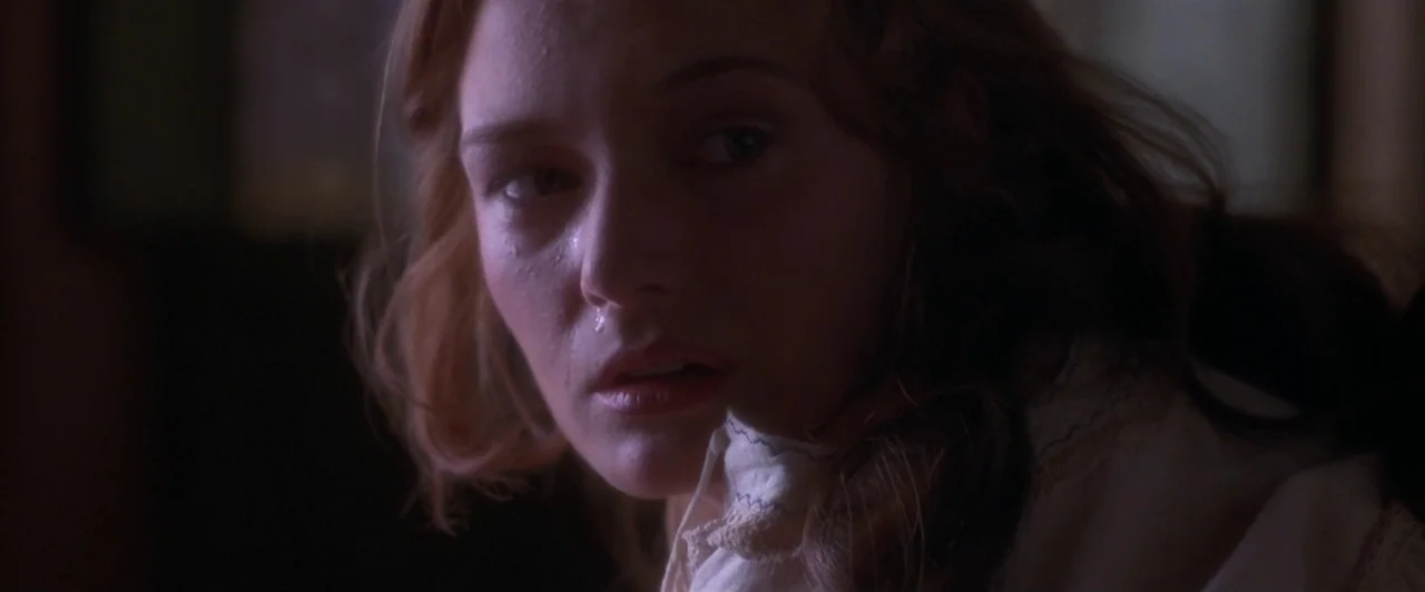 Dangerous Beauty (1998) movie still: closeup — A dark interior space with minimal light sources casting soft shadows across the frame. A woman with…
