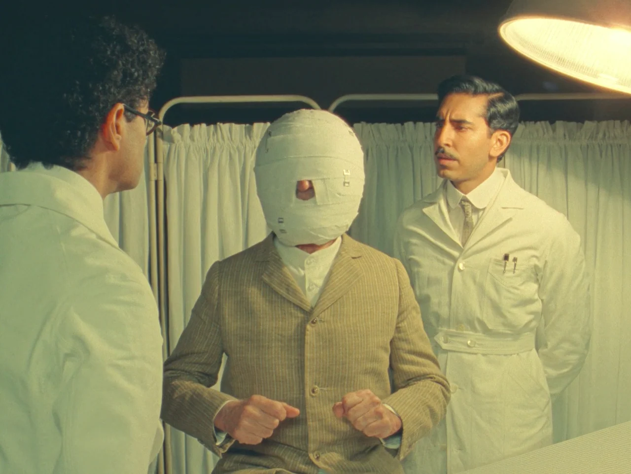 The Wonderful Story of Henry Sugar (2023) movie still: medium — A medical examination room features white curtains in the background and bright…