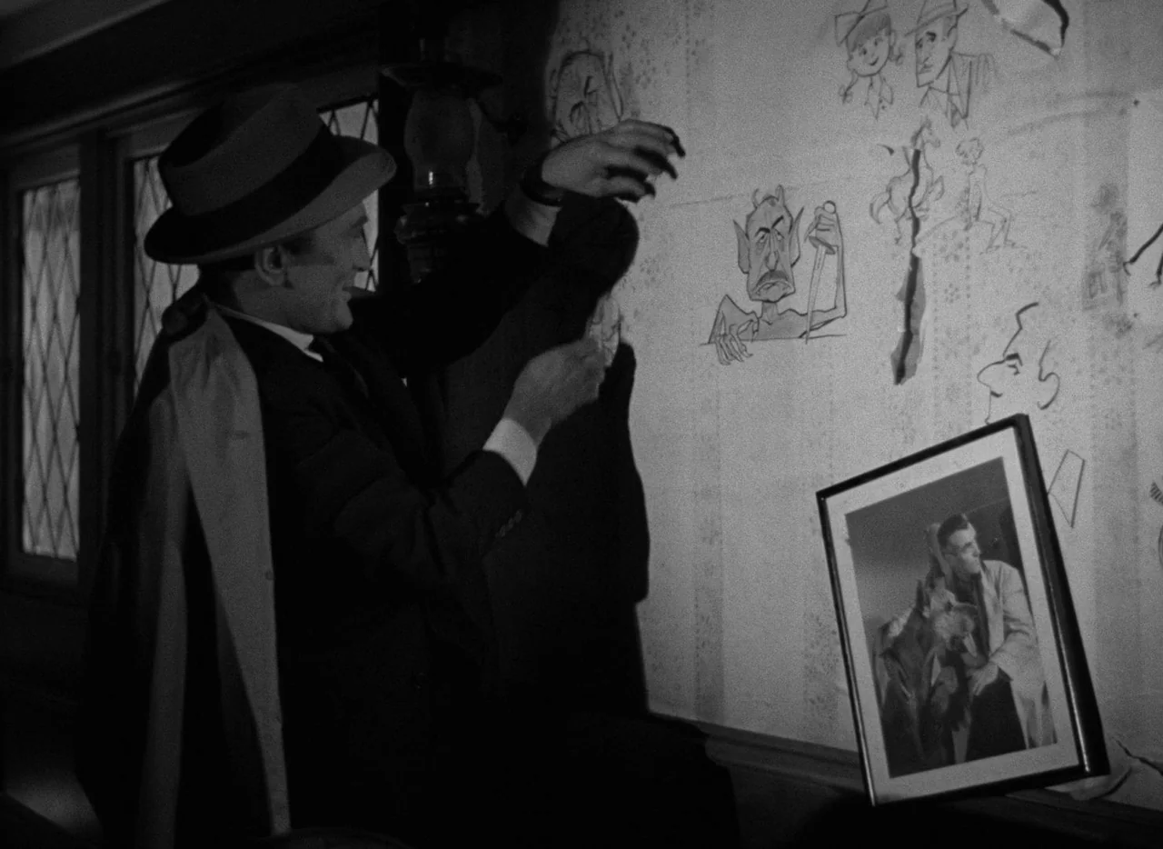 The Bad and the Beautiful (1952) movie still: medium — A man in a fedora stands by a wall adorned with various ink drawings. He carefully attaches a…