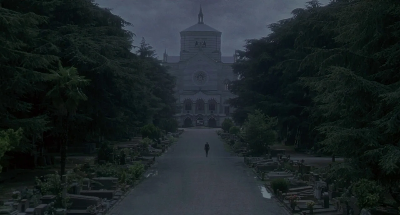 Making of: I Am Love (2009) movie still: establishing — A long paved path flanked by dense pine trees leads toward an ornate mausoleum. A small…