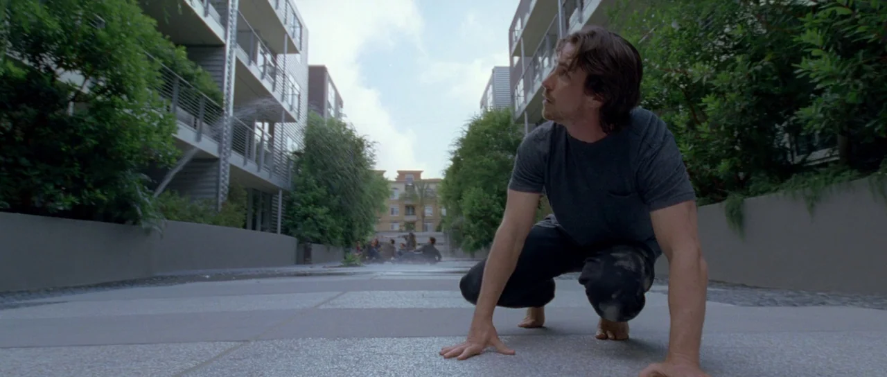 Knight of Cups (2015) movie still: medium — A modern paved walkway flanked by apartment buildings with manicured greenery and steel balconies. A…