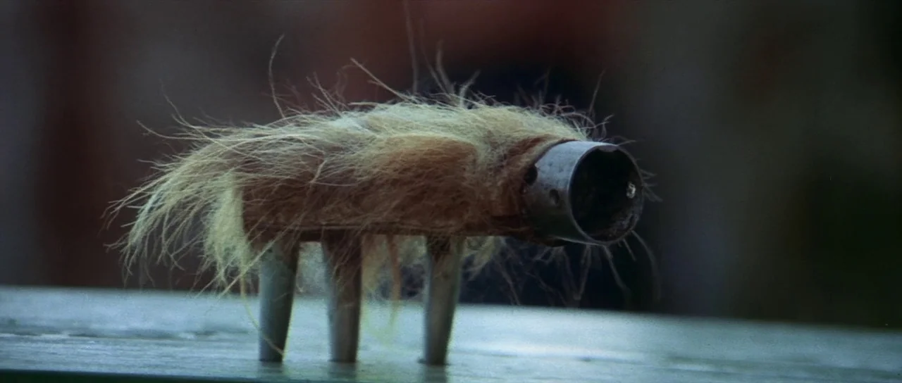 Enter The Dragon (1973) movie still: closeup — A fur-covered, four-legged device with a metallic snout sits on a horizontal surface. The object is…