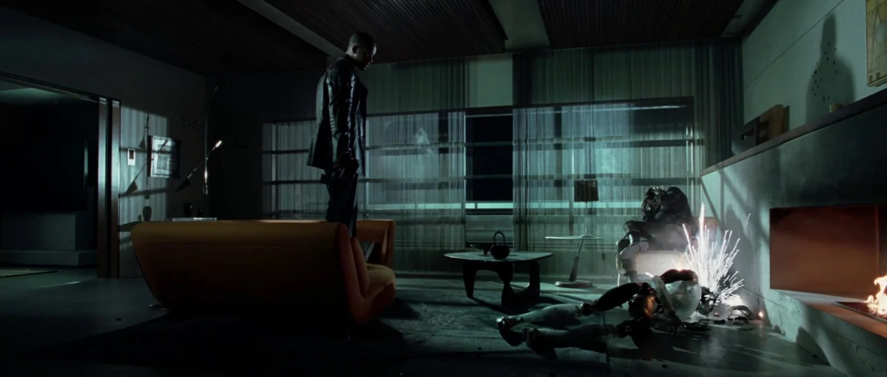 I, Robot (2004) movie still: wide — A modern, minimalist home with low-slung furniture and a fireplace at night. A man stands over a damaged,…