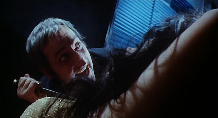 5 Dolls for an August Moon (1970) movie still: closeup — A dimly lit interior space with a window covered by dark horizontal blinds. A man holding a…