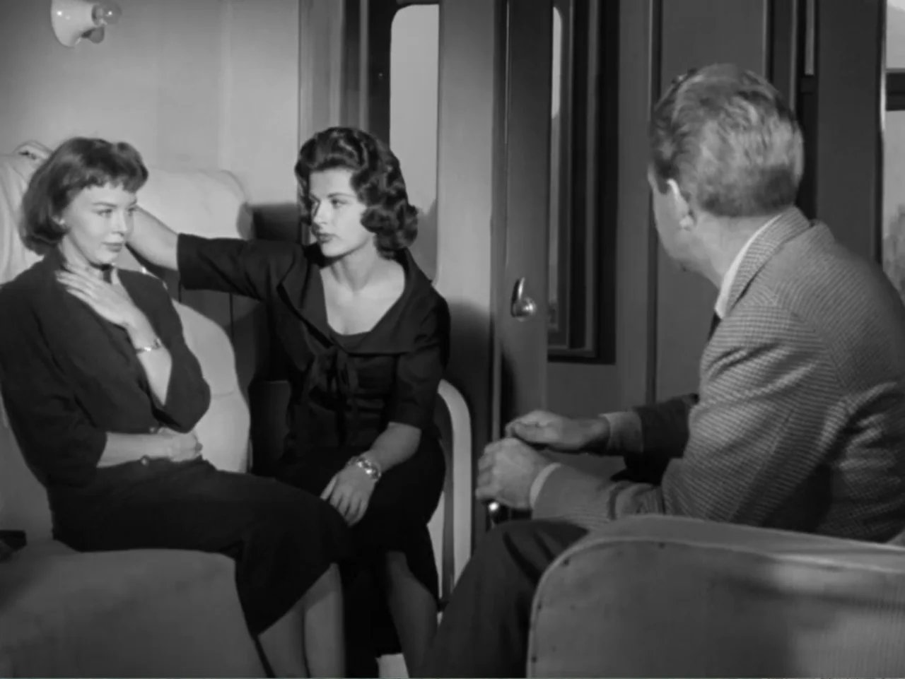 The Crawling Eye (1958) movie still: medium — A 1950s train compartment features upholstered seats and windows looking onto a landscape. Two women…