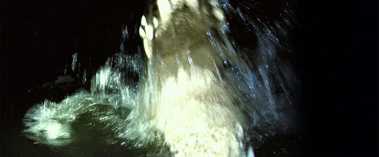 Black Water: Abyss (2020) movie still: closeup — A dark swamp environment at night with rippling black water. An open crocodile jaw filled with…