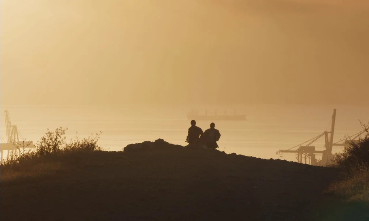 The Last Black Man in San Francisco (2019) movie still: wide — A high vantage point overlooks a hazy harbor with distant industrial cranes and…